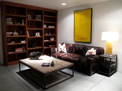 A large yellow abstract above a leather sofa in a living room lined with bookshelves