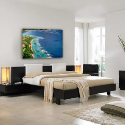A coastal landscape painting above a bed in a white bedroom